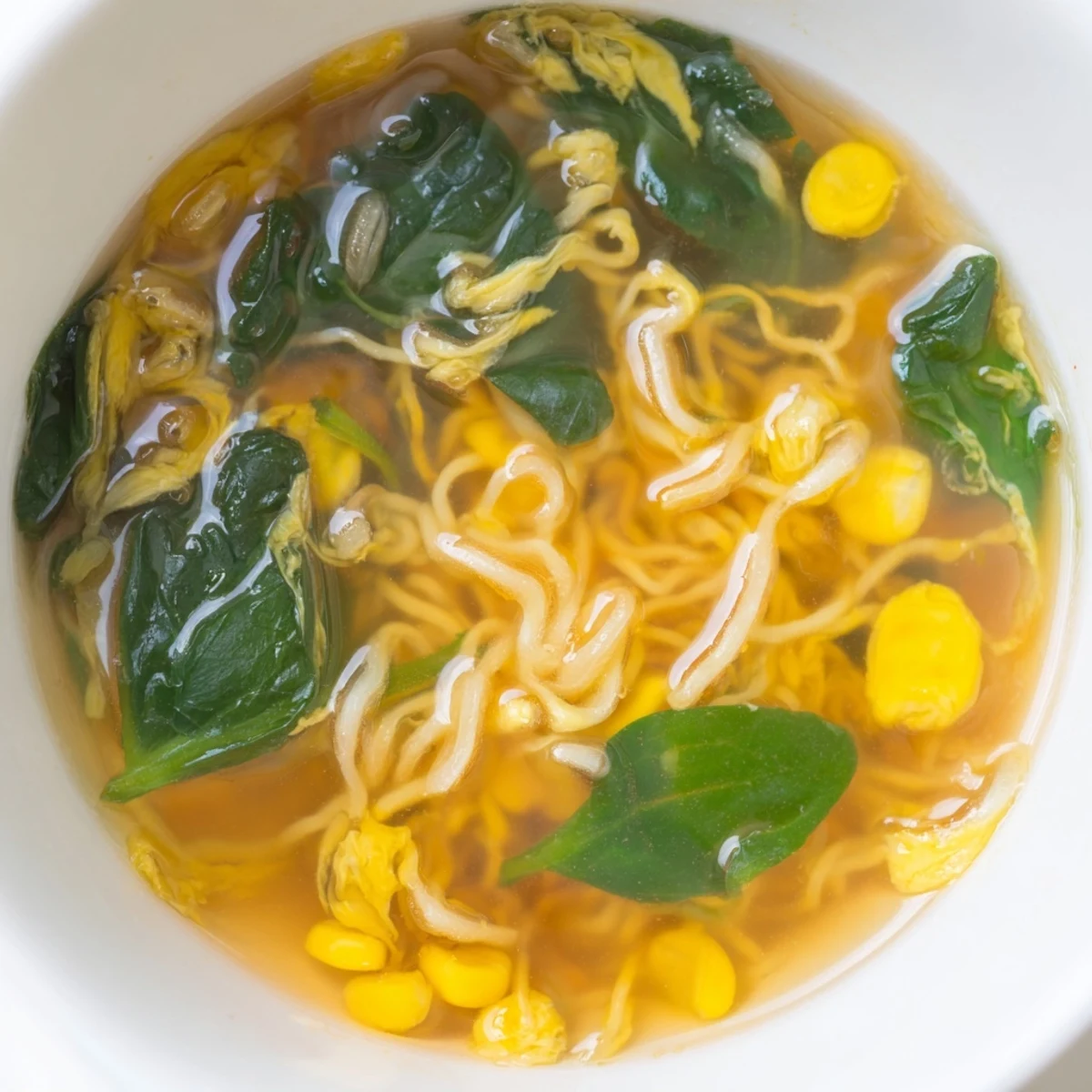 Steaming bowls of Elevated Ramen Egg Drop Soup feature tender noodles and bright green spinach.