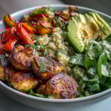 Paprika Roasted Vegetable Quinoa Bowl with golden pan-fried chicken, creamy avocado, and crisp lemon salad on a fork.