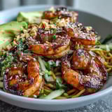 Juicy grilled shrimp rest on sesame dressed noodles, topped with bean sprouts, scallions, and cilantro in a vibrant, easy bowl.