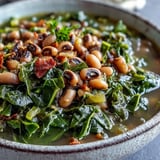 Tender black-eyed peas and simmered collard greens in a rustic pot, seasoned with smoked paprika and ready to serve.