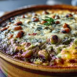 Hot Black-Eyed Pea Dip in a baking dish, melted cheddar and golden bubbles, ready to scoop with tortilla chips.