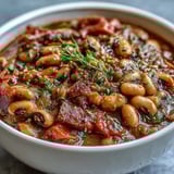 Tender Greek-Style Slow Cooker Black-Eyed Peas topped with feta, parsley, and a lemon wedge, served in a shallow bowl.