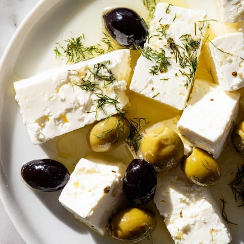 Briny Turkish Olives & Cheese Board, featuring creamy cheeses drizzled with golden honey and warm bread.