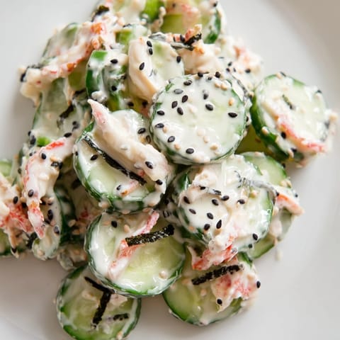 California Roll Cucumber Salad garnished with nori strips and pickled ginger on a white ceramic bowl.