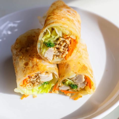 Freshly pan-fried Garlicky Pulled Chicken Wraps served on a wooden board with lemon wedges.  