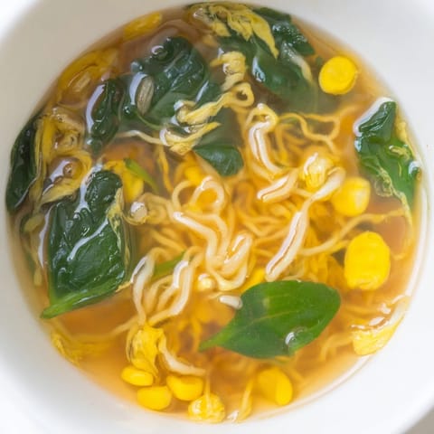 Steaming bowls of Elevated Ramen Egg Drop Soup feature tender noodles and bright green spinach.