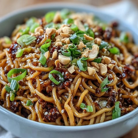 Spicy Chili Crisp Noodles dish, glistening with savory sauce and fresh scallions.