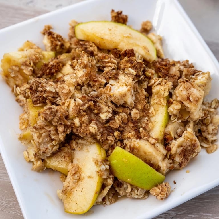 Bubbling Rustic Apple and Cinnamon Crumb Bake with a cinnamon-spiced apple filling beneath.