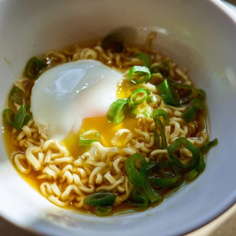 Close-up of savory upgraded instant ramen, garnished with fresh scallions and rich broth.