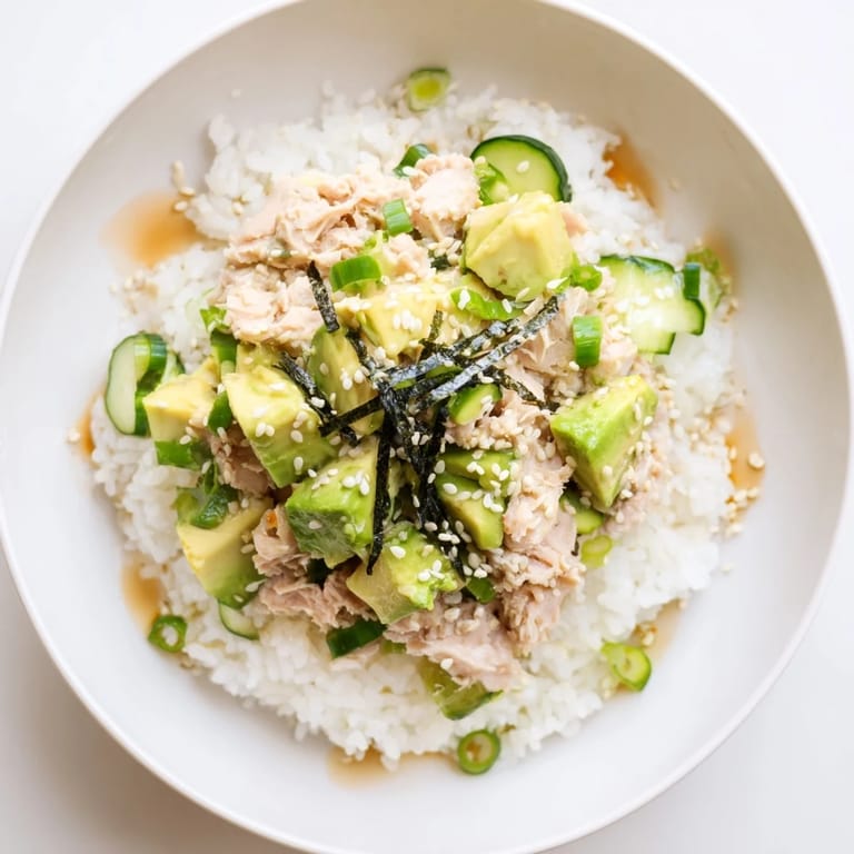 This Tuna Avocado Rice Bowl is garnished with toasted sesame seeds and nori, ready for a quick meal.
