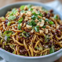Spicy Chili Crisp Noodles dish, glistening with savory sauce and fresh scallions.